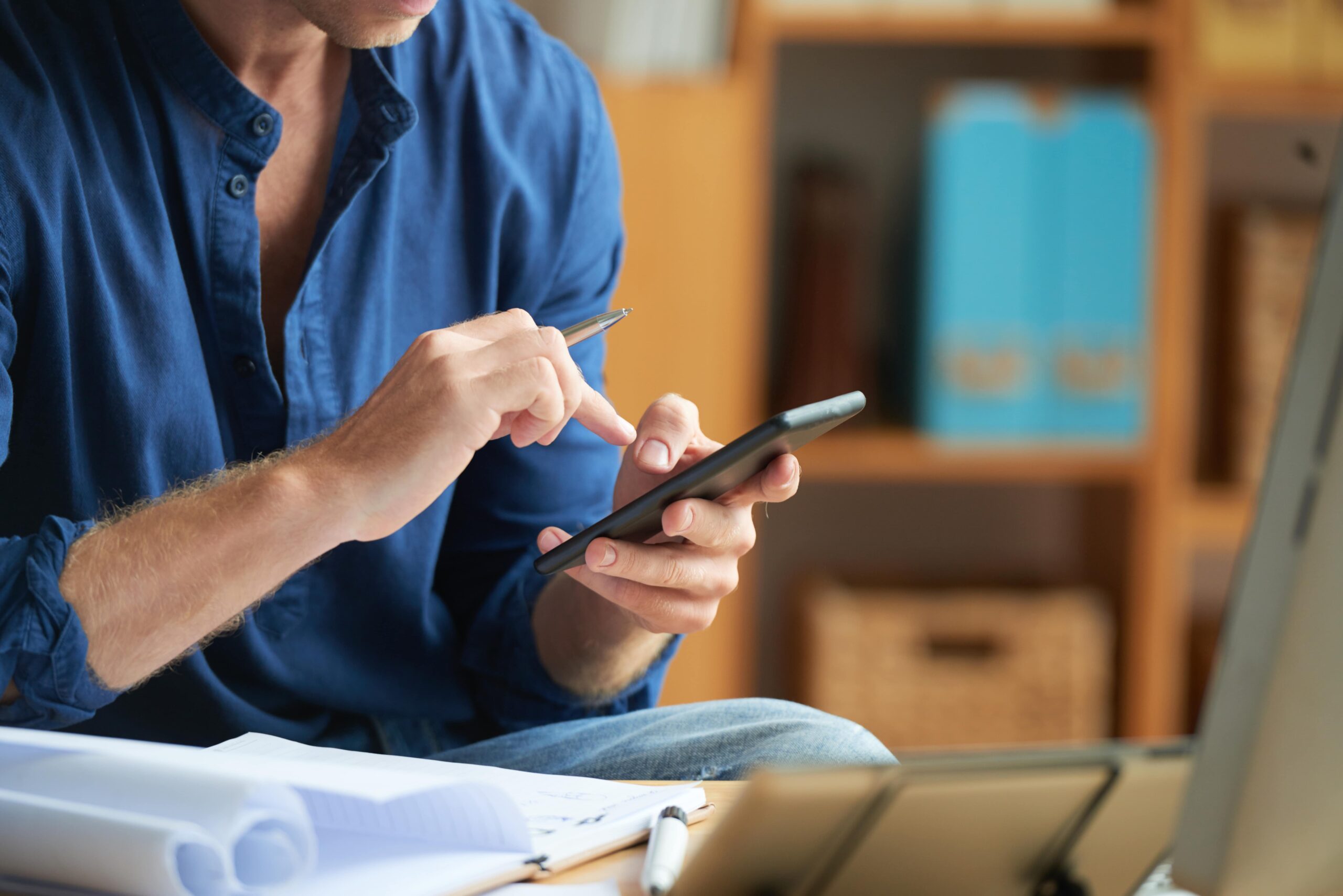 casually-dressed-unrecognizable-man-using-smartphone-work-office-min
